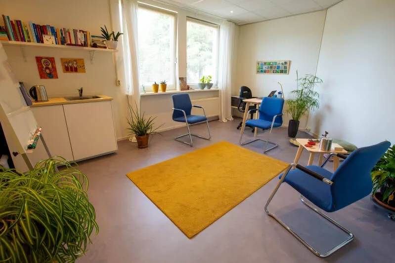 De spreekkamer van Nynke Groot in Leiden — met gele tapijt en blauwe stoelen